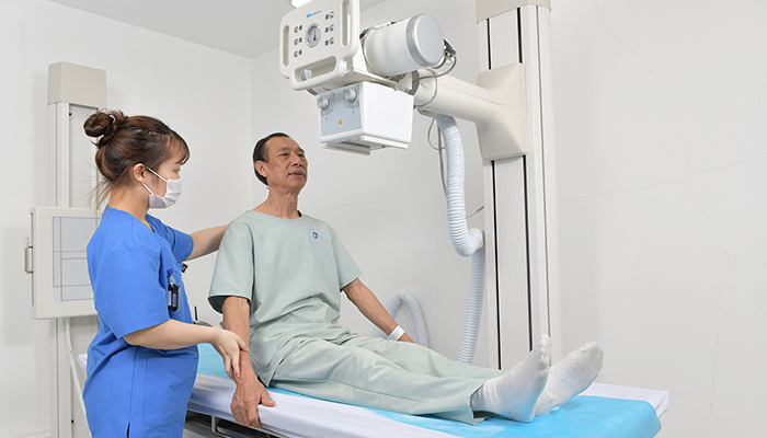 Kỹ thuật viên hướng dẫn khách hàng ngồi đúng vị trí khi chụp X-quang